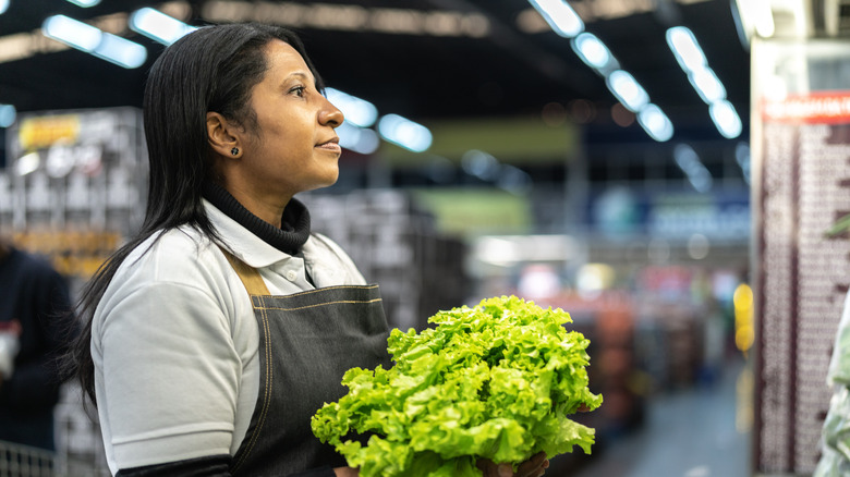 Grocery store employee holding lettuce