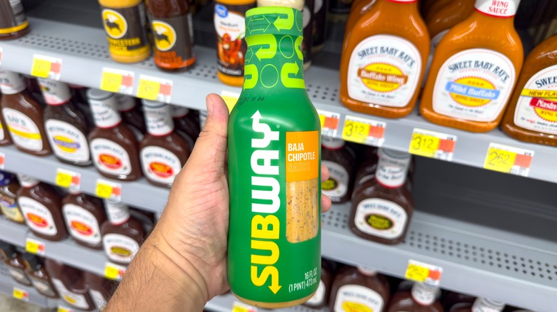 Man holding a bottle of Subway's Baja Chipotle sauce in a grocery store