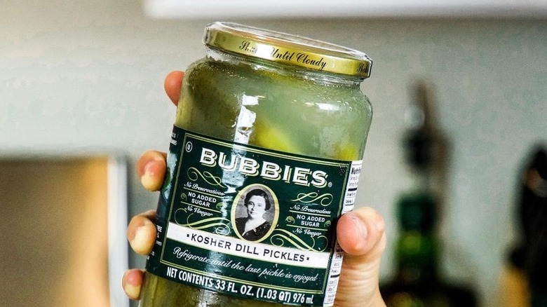 Hand holding a jar of Bubbies Kosher Dill Pickles