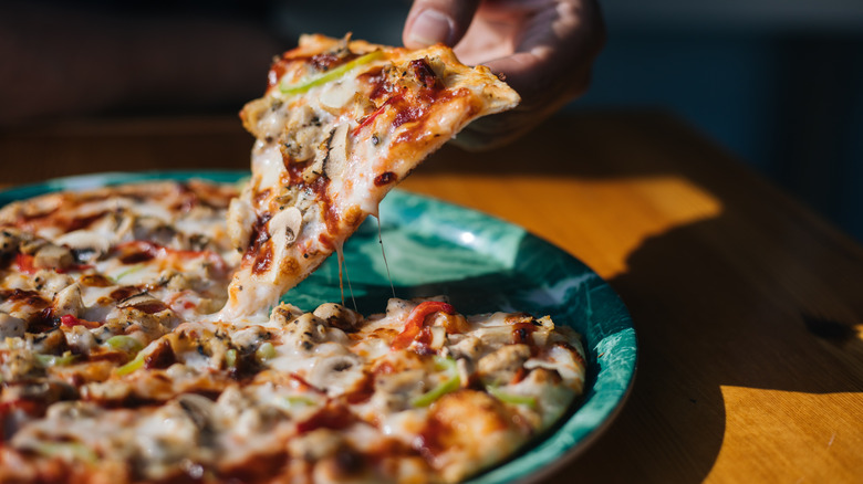 Person grabbing slice of frozen pizza