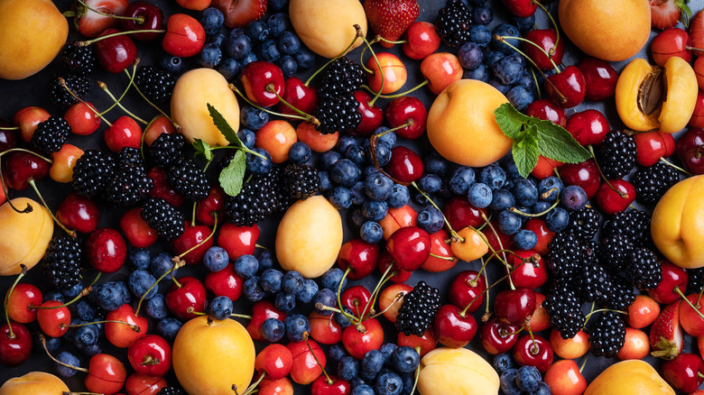 Blueberries, cherries, blackberries, and apricots rest on a table