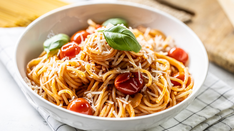 A bowl of spaghetti with tomatoes and fresh herbs