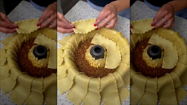 Person layering meat and noodles in Bundt pan lasagna