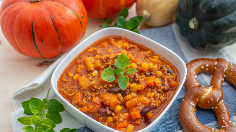 Bowl of pumpkin chili with pumpkins in the background