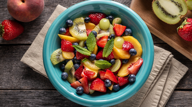 Fruit medley with peaches, kiwi, grapes, and berries in a blue bowl