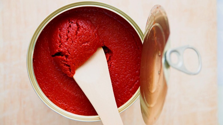 Scooping tomato paste out of can