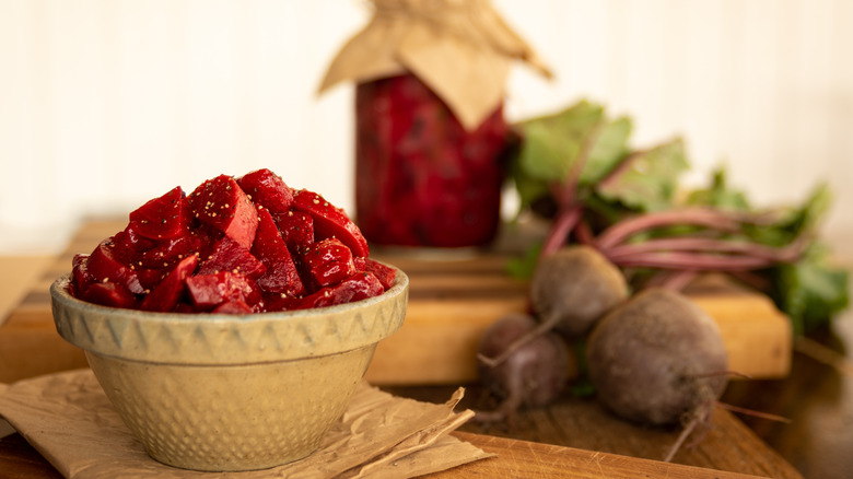 A bowl of Harvard beets with jar and fresh beets in background