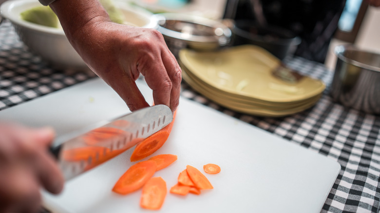 Chopping whole carrots with knife
