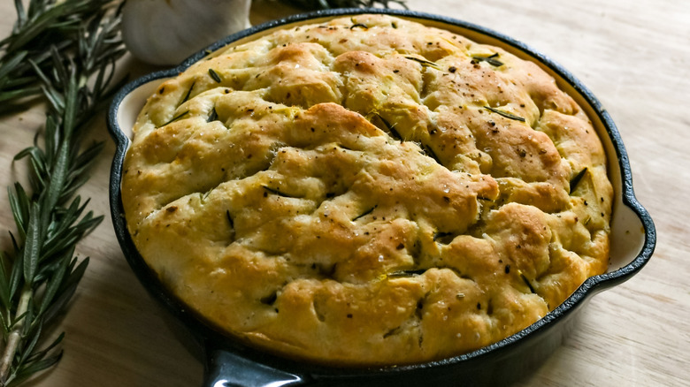 Focaccia bread in a cast iron skillet with rosemary and garlic