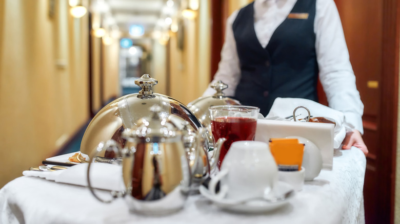 Hotel staff bringing plated room service to a room
