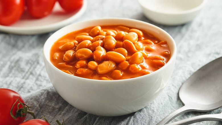 A bowl of cooked beans in tomato sauce on a table.