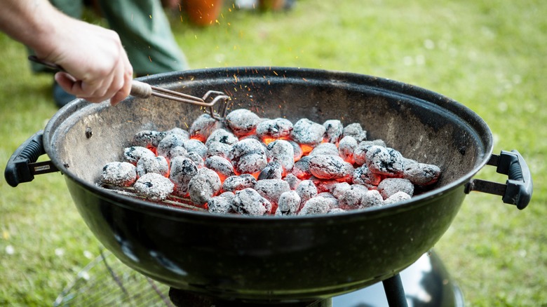 Dispersing coals on grill with tongs