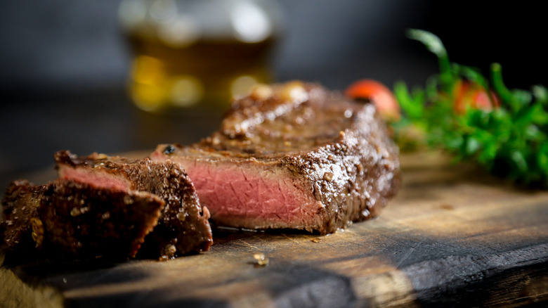 Medium-rare grilled steak on a wooden board. 