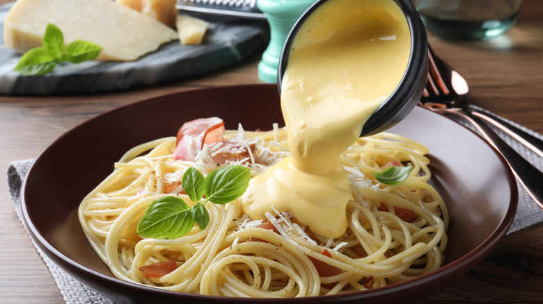 Creamy cheese sauce being poured on pasta