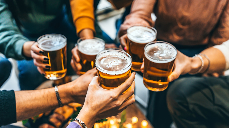 Six hands toasting glasses of beer