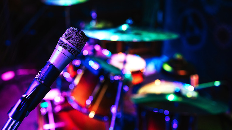 Microphone under purple lighting in front of drum set