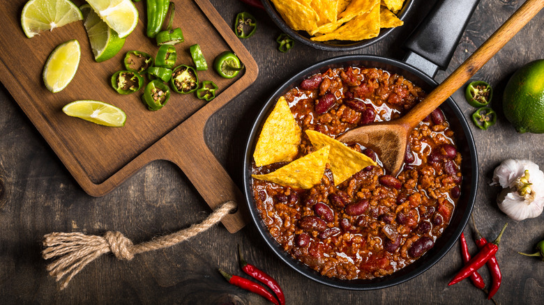 Meat chili with beans cooking in a pot with a wooden spoon