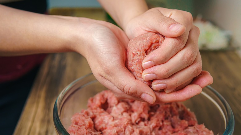 Person forming burgers from raw meat