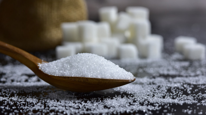 Sugar on a spoon with cubes in the background