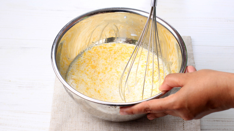 Whisking melted butter and milk in a bowl