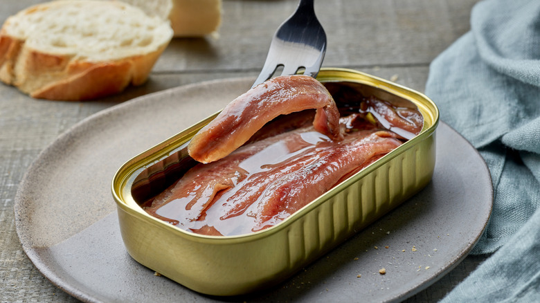 A plate with a tin of anchovies and a fork