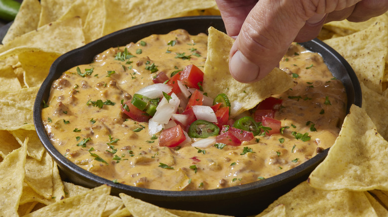 Person dipping chip in queso