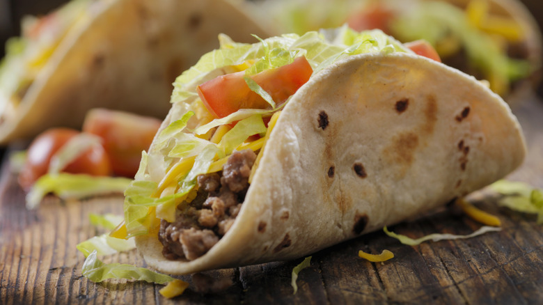 Soft shell ground beef tacos with shredded lettuce, tomato, and cheese