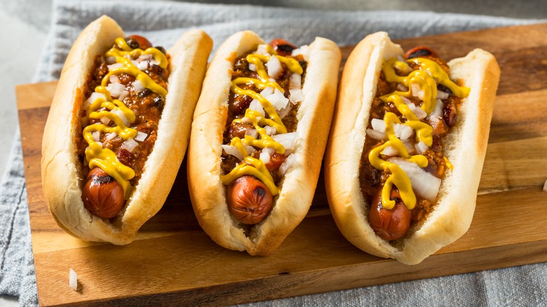 Three Coney Island dogs with mustard, onions, and meat sauce