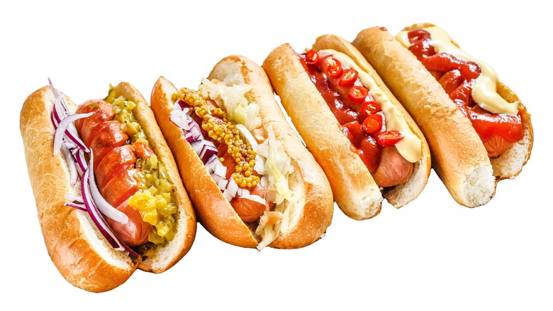 Four hot dogs in buns with different toppings