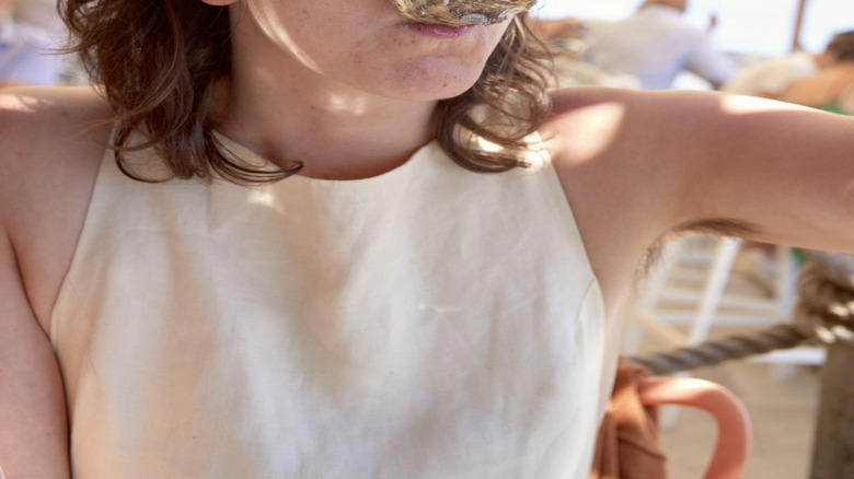 A person eating an oyster from the shell