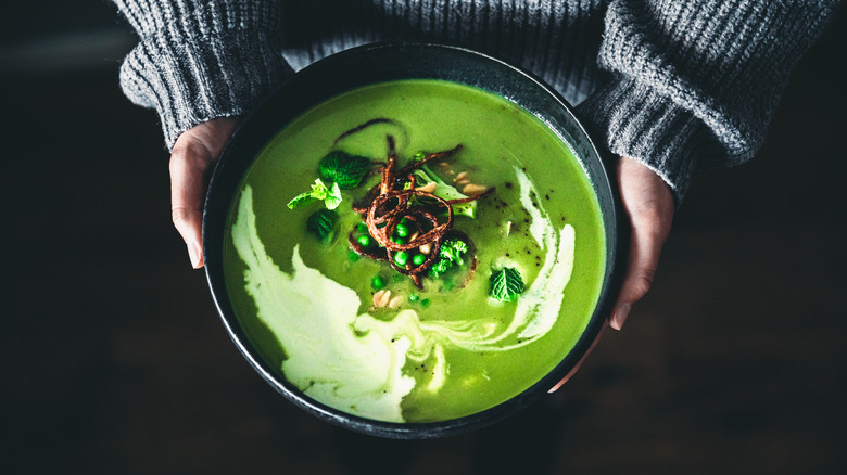white hands holding green soup