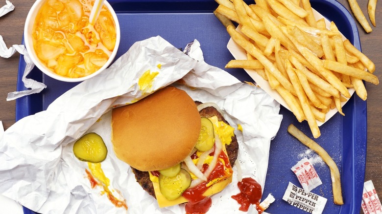 Fast food burger and fries in plastic and paper packaging