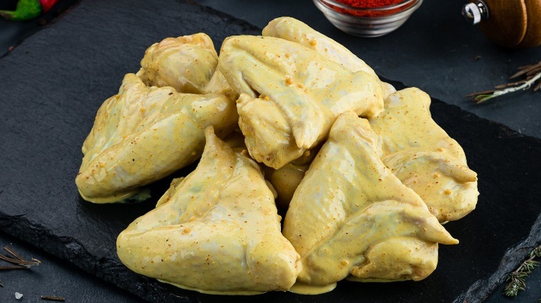 Chicken pieces basted in mustard, ready for breading