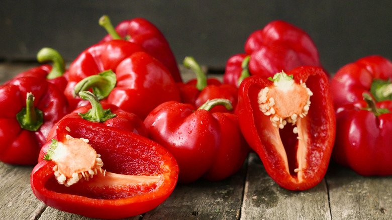 Several red bell peppers, some sliced in half.