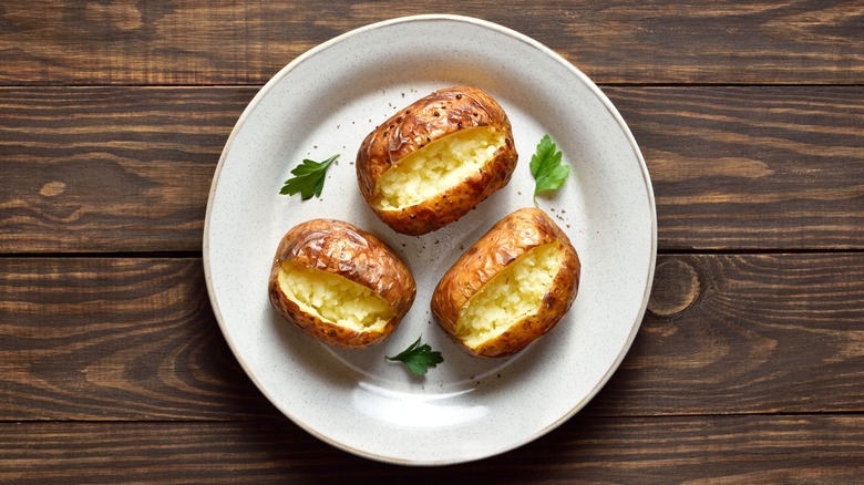 Three baked potatoes on a white plate