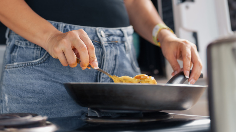 Woman pan frying eggs for breakfast sandwich