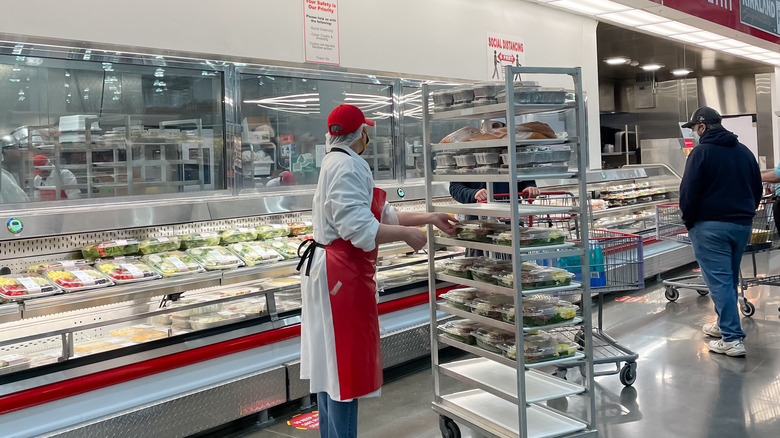 Costco employee restocking the deli food platters