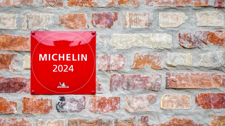 A red sign that reads "Michelin 2024" affixed to an exterior brick wall.