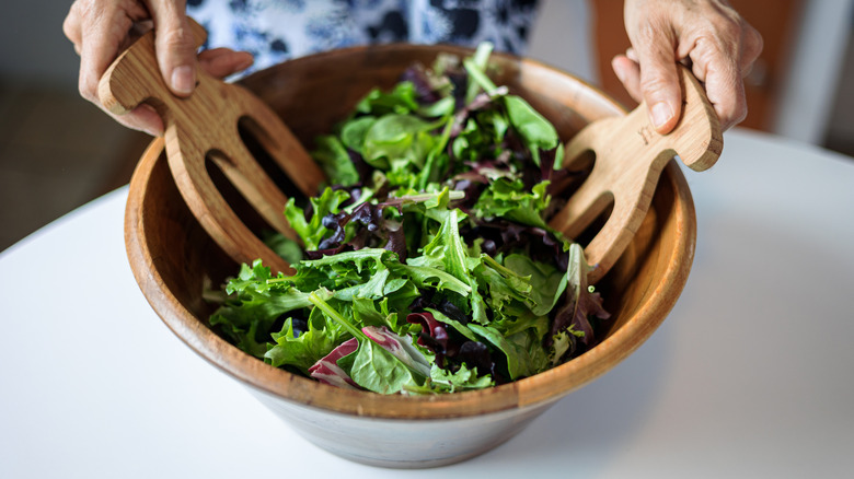 Hands tossing a green salad