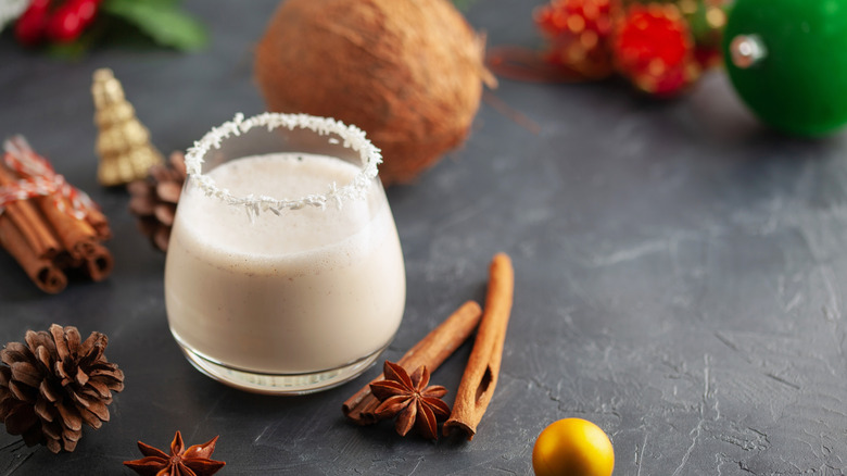 Glass of coquito with cinnamon, star anise, and pine cones