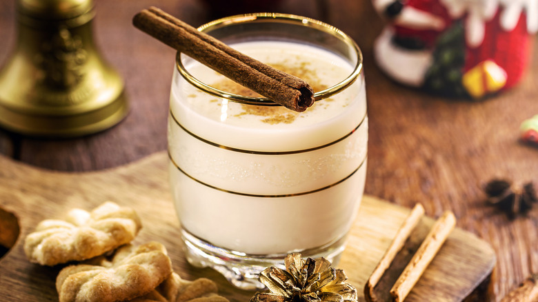 Coquito with cinnamon stick in glass cup with Christmas decor