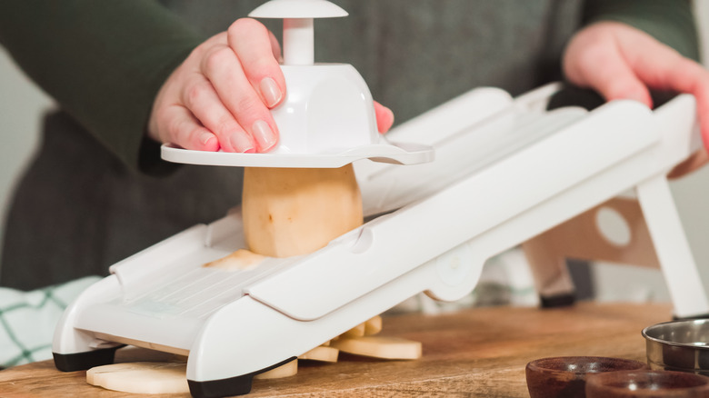 Person slicing potatoes with a mandolin