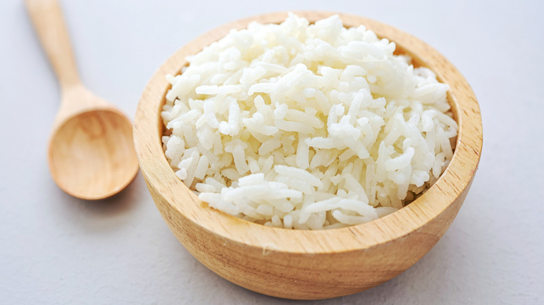 A small wooden bowl of white rice with a wooden spoon