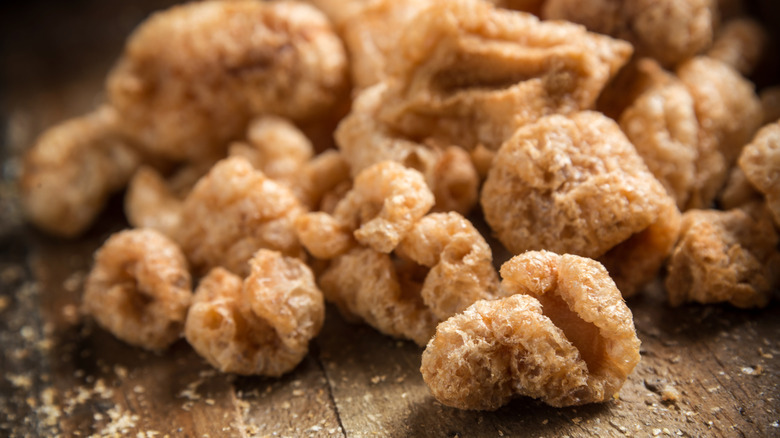 Heap of crumbly pork rinds on wood table