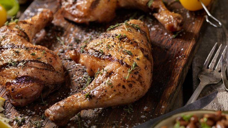 Seasoned chicken thighs and drumsticks resting on a cutting board.