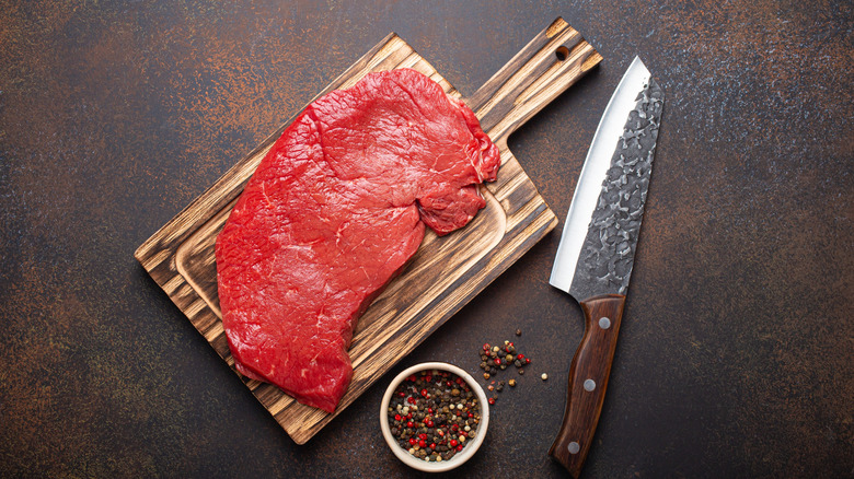 Raw top round steak served on cutting board