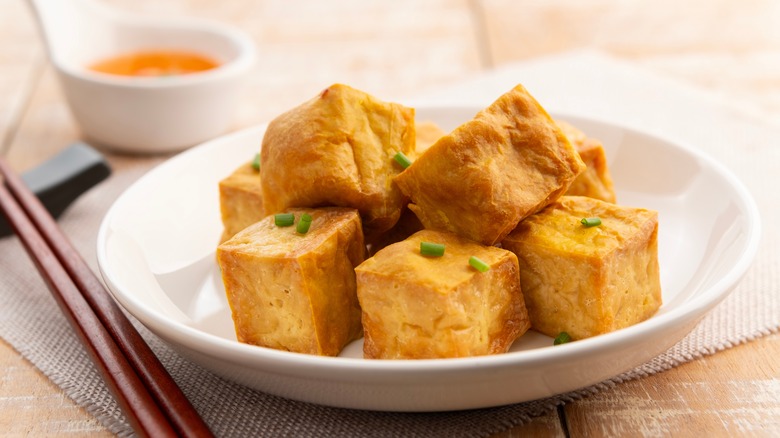 crispy tofu pyramid next to sauce and chopsticks