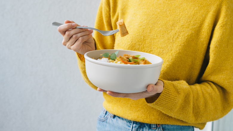 person eating tofu out of a bowl