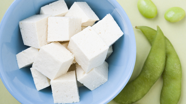 tofu in ceramic bowl next to soybeans