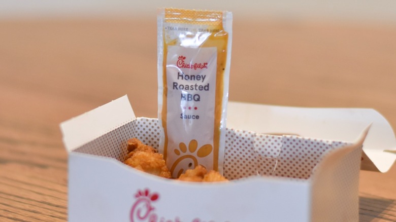 A packet of honey roasted barbecue by a box of nuggets on a wooden table